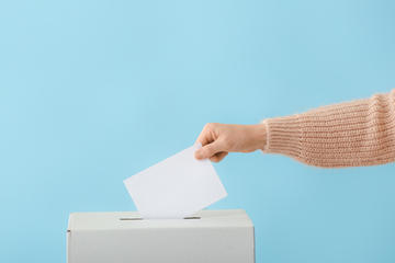 Voting woman near ballot box on color background